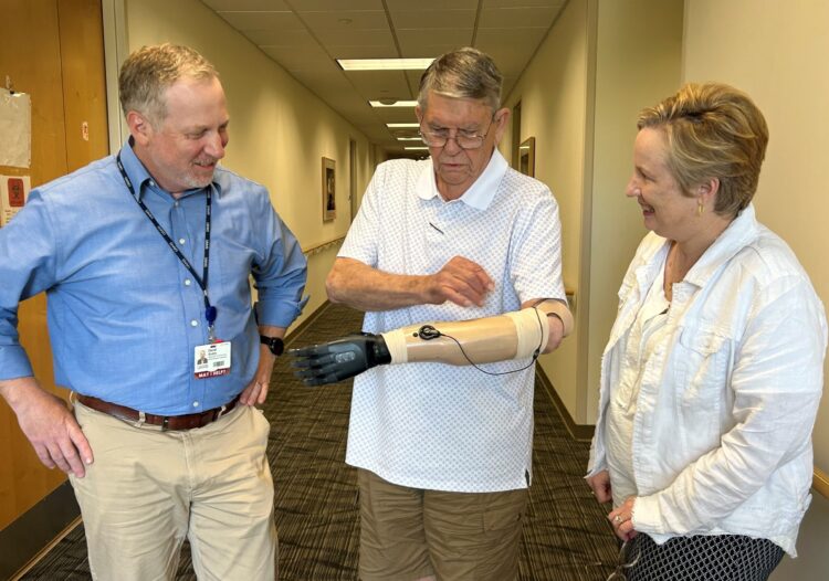 Dewey Hickey shows the experimental prosthetic system to the UAMS Translational Research Institute's David Avery, senior director of Clinical Research Operations, and Laura James, M.D., director. Avery and James helped facilitate the research collaboration between UAMS and the University of Arkansas' I³R team.