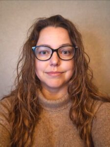 Ashley Pike, PhD Ashley Pike is a woman with long brown hair and wearing glasses.