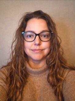 Ashley Pike, PhD Ashley Pike is a woman with long brown hair and wearing glasses.
