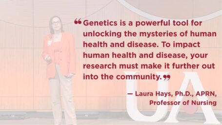 Photo of Laura Hayes on stage. She is wearing a red jacket over tan pants. Quote on image reads: “Genetics is a powerful tool for unlocking the mysteries of human health and disease. To impact human health and disease, your research must make it further out into the community.”